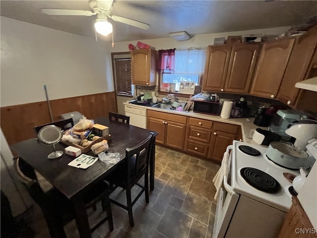 kitchen with ceiling fan, white appliances, sink, and wood walls