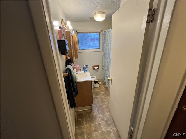 bathroom featuring vanity, a textured ceiling, and toilet