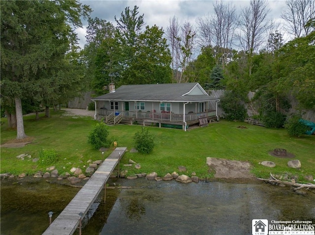 back of house featuring a deck with water view, a fire pit, and a lawn