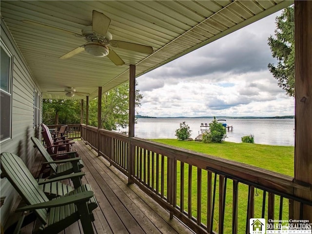 deck with a water view, ceiling fan, and a lawn