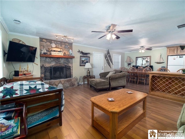 living room with hardwood / wood-style flooring, a stone fireplace, and ornamental molding