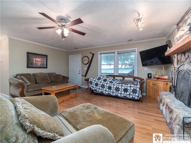 living room featuring ornamental molding, a stone fireplace, and light hardwood / wood-style floors