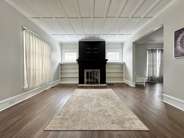 unfurnished living room with a large fireplace, ornamental molding, and dark hardwood / wood-style floors