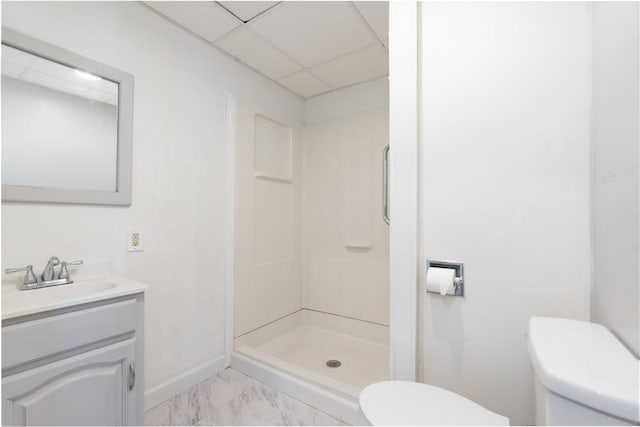 bathroom featuring walk in shower, vanity, toilet, and a drop ceiling