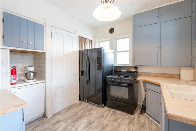 kitchen featuring sink, light hardwood / wood-style flooring, gray cabinetry, backsplash, and black appliances