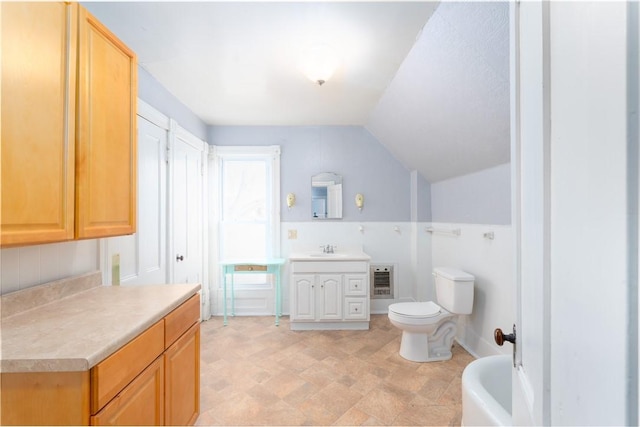 bathroom with vaulted ceiling, heating unit, vanity, a washtub, and toilet