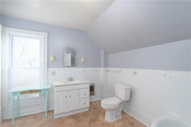 bathroom featuring vanity, vaulted ceiling, heating unit, and toilet