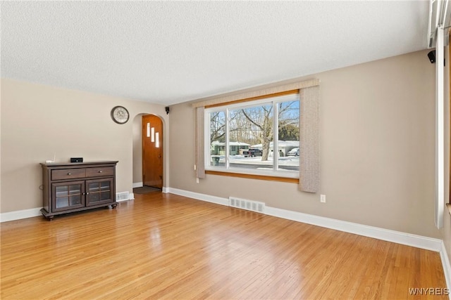 unfurnished living room featuring a textured ceiling and light hardwood / wood-style flooring