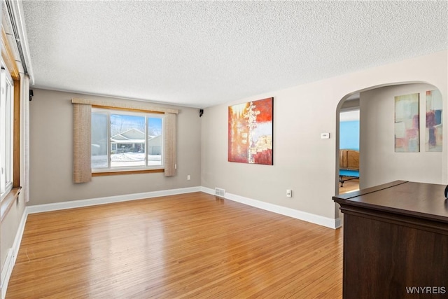 spare room with a textured ceiling and light wood-type flooring