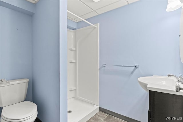 bathroom with a paneled ceiling, vanity, tile patterned floors, toilet, and walk in shower