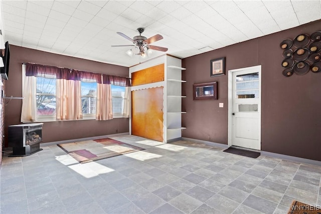 interior space with a wood stove and ceiling fan