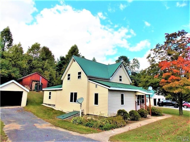 view of home's exterior with a garage, an outdoor structure, and a yard