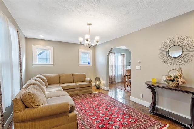 living room featuring an inviting chandelier, dark hardwood / wood-style flooring, and a textured ceiling