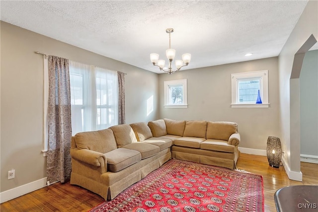 living room featuring hardwood / wood-style flooring, an inviting chandelier, and a textured ceiling