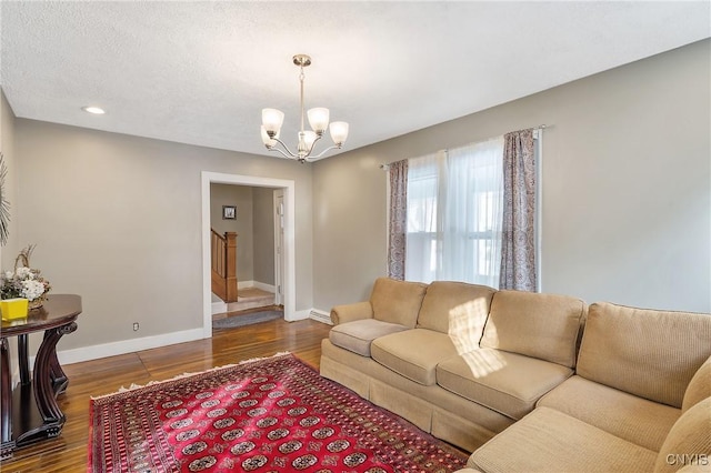 living room featuring dark hardwood / wood-style flooring, a notable chandelier, and a textured ceiling