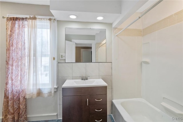 bathroom with vanity, decorative backsplash, bathtub / shower combination, and tile walls