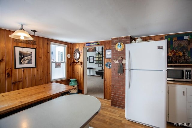 kitchen featuring pendant lighting, wooden walls, white fridge, and light hardwood / wood-style flooring