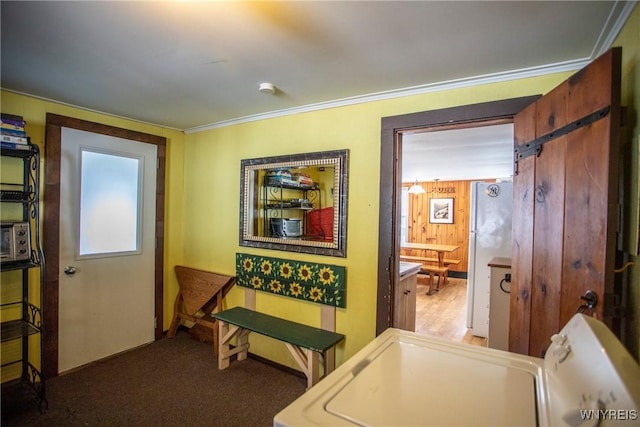 interior space with washer / dryer, ornamental molding, a barn door, and wood walls