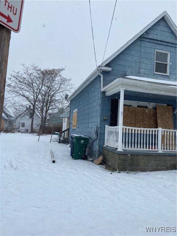 snow covered property with covered porch