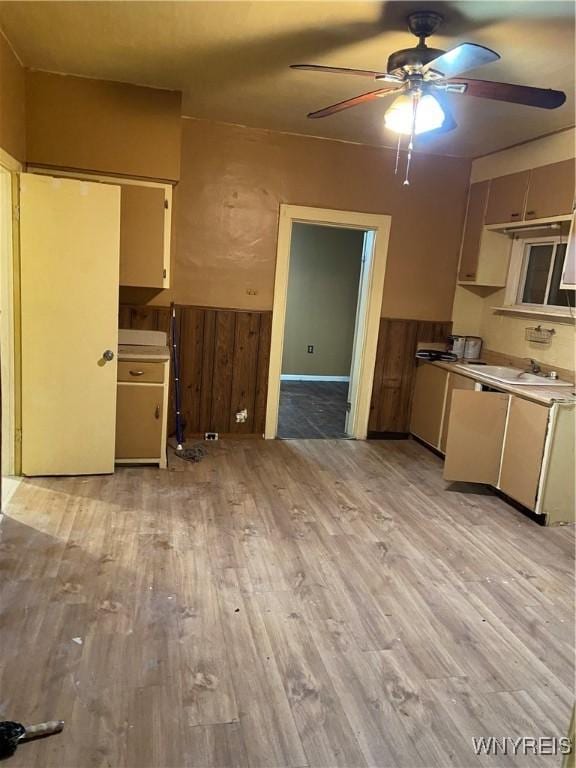 kitchen featuring wood walls, ceiling fan, and light wood-type flooring