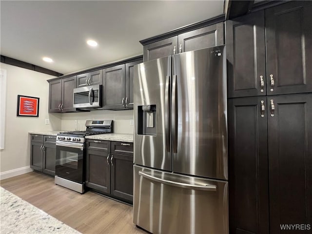 kitchen with light stone counters, appliances with stainless steel finishes, and light hardwood / wood-style flooring