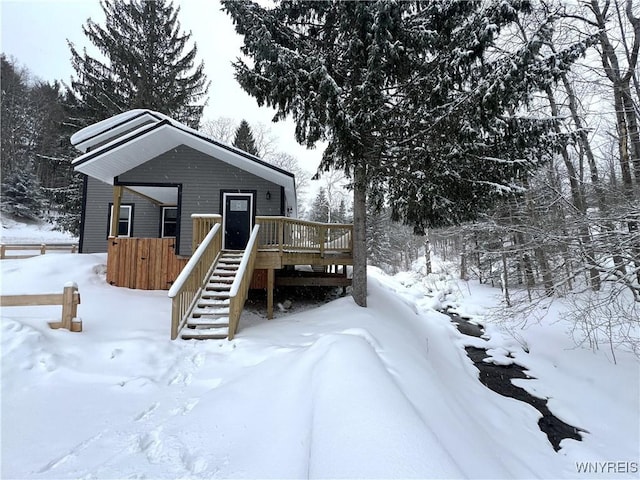 snow covered back of property featuring a wooden deck