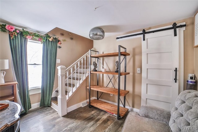 staircase featuring wood-type flooring, a barn door, and a healthy amount of sunlight