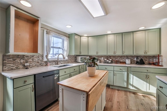 kitchen with sink, dishwasher, green cabinets, backsplash, and light wood-type flooring