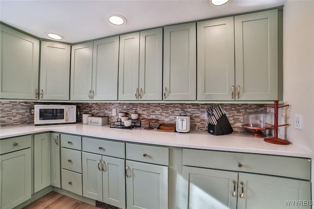 kitchen featuring light hardwood / wood-style floors, green cabinets, and decorative backsplash