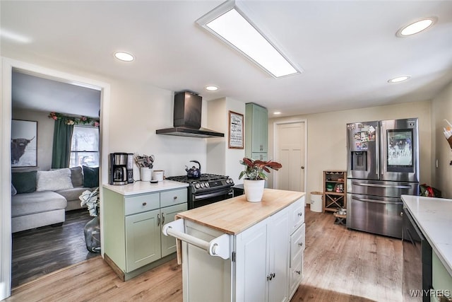 kitchen featuring light hardwood / wood-style flooring, green cabinets, stainless steel appliances, white cabinets, and wall chimney exhaust hood