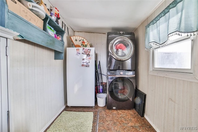 laundry room featuring stacked washer and clothes dryer and wooden walls