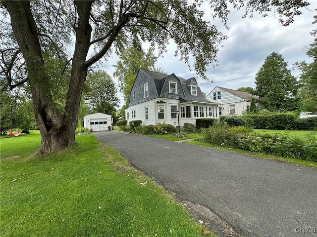 new england style home featuring a garage, an outdoor structure, and a front lawn