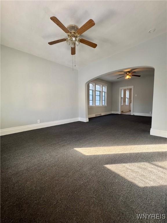 unfurnished room with ceiling fan and dark colored carpet