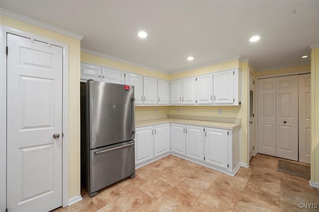 kitchen featuring white cabinetry, stainless steel fridge, and ornamental molding