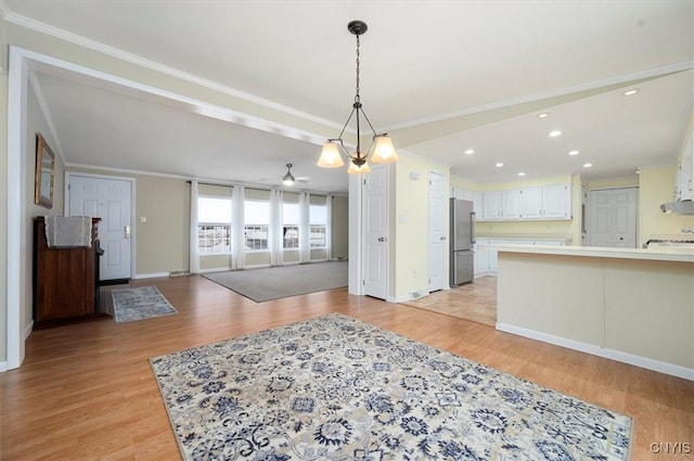 interior space with light hardwood / wood-style flooring, crown molding, stainless steel fridge, and white cabinets