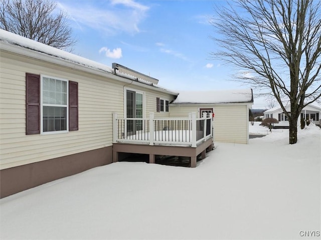 snow covered rear of property with a deck