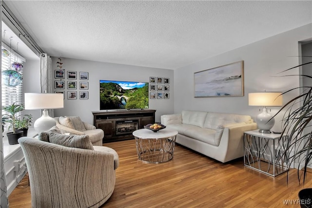 living room featuring hardwood / wood-style flooring, a fireplace, and a textured ceiling