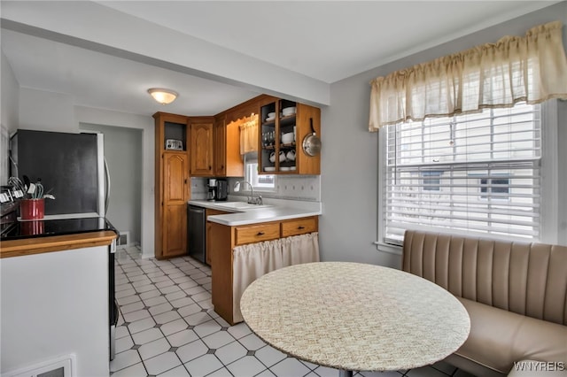 kitchen featuring sink, stainless steel refrigerator, radiator, dishwasher, and kitchen peninsula