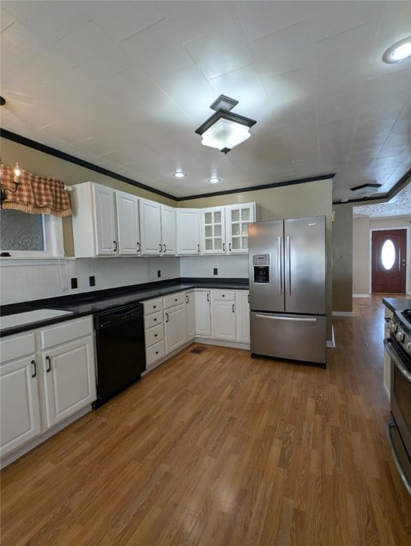 kitchen with appliances with stainless steel finishes, hardwood / wood-style floors, and white cabinets