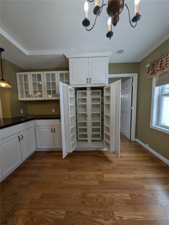 kitchen with white cabinetry, hardwood / wood-style flooring, pendant lighting, and an inviting chandelier