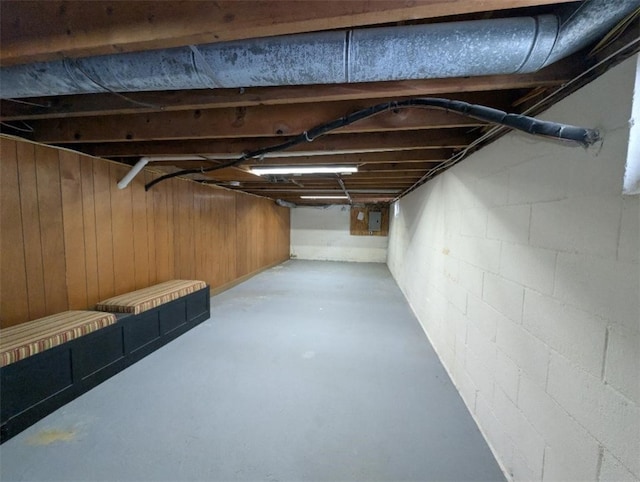 basement with electric panel and wood walls