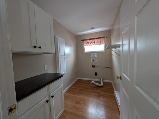 laundry area with hookup for a washing machine, light hardwood / wood-style flooring, and cabinets