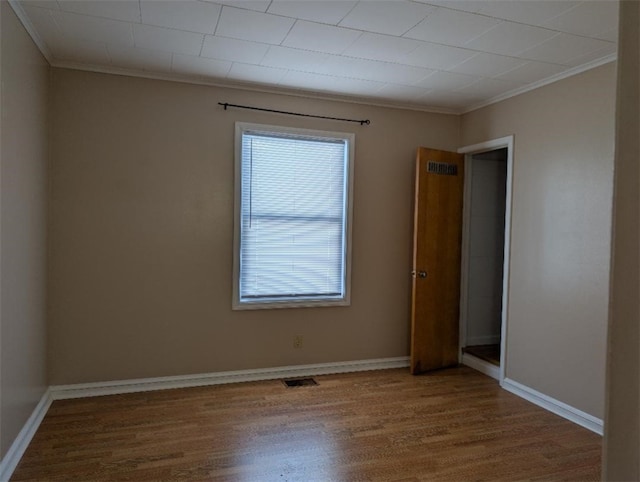 spare room with hardwood / wood-style floors and crown molding