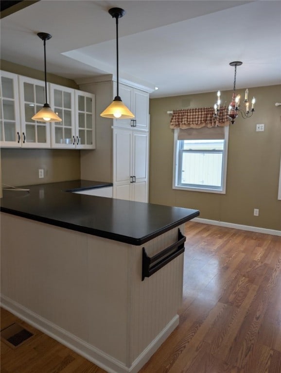 kitchen featuring decorative light fixtures, wood-type flooring, and white cabinets