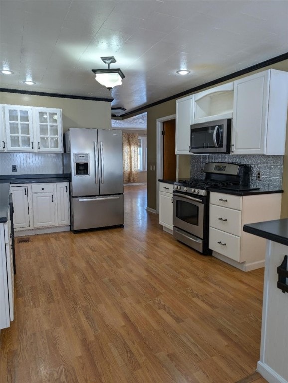 kitchen featuring white cabinetry, tasteful backsplash, light wood-type flooring, ornamental molding, and appliances with stainless steel finishes