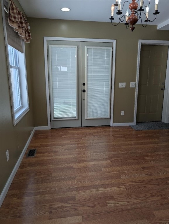 entrance foyer featuring dark hardwood / wood-style floors, a chandelier, and french doors