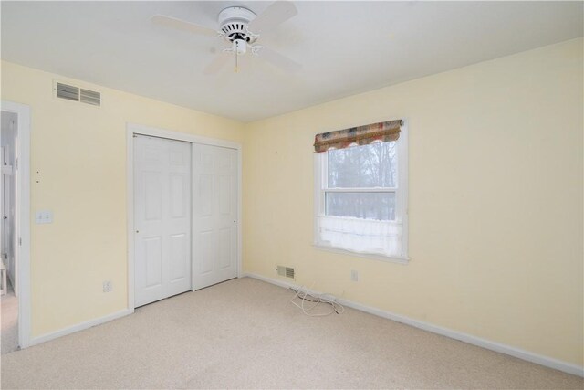 unfurnished bedroom with light carpet, ceiling fan, and a closet