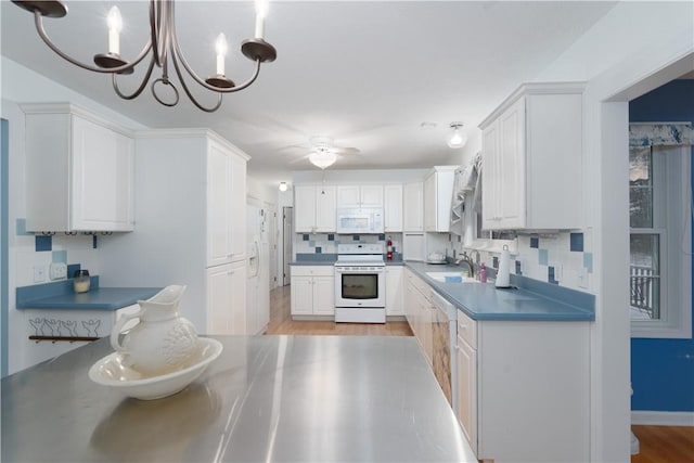 kitchen featuring tasteful backsplash, decorative light fixtures, light wood-type flooring, white appliances, and white cabinets