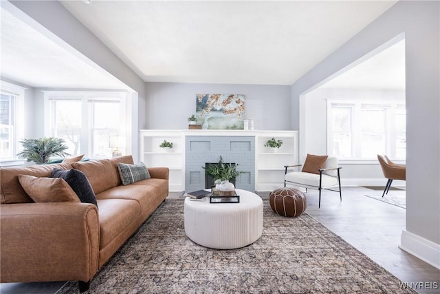 living room featuring a brick fireplace and dark wood-type flooring