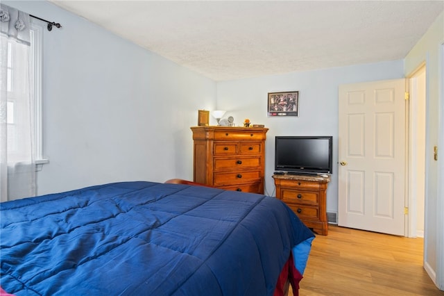 bedroom featuring light hardwood / wood-style flooring and a textured ceiling